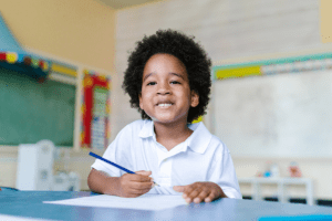 How to Decide If Private School is Right for Your Child, image of a young child smiling with a pencil and paper